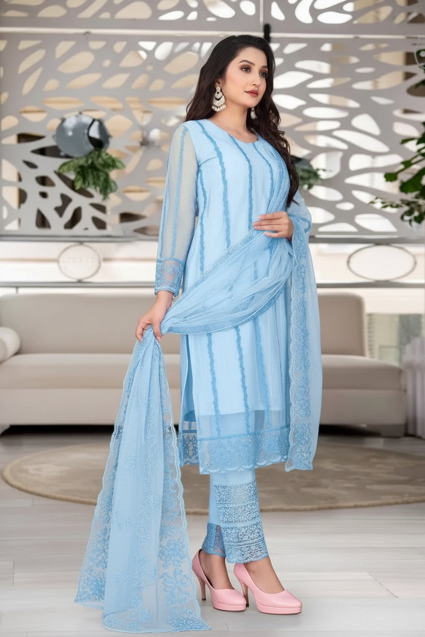 Woman in a light blue traditional outfit standing in a modern living room.